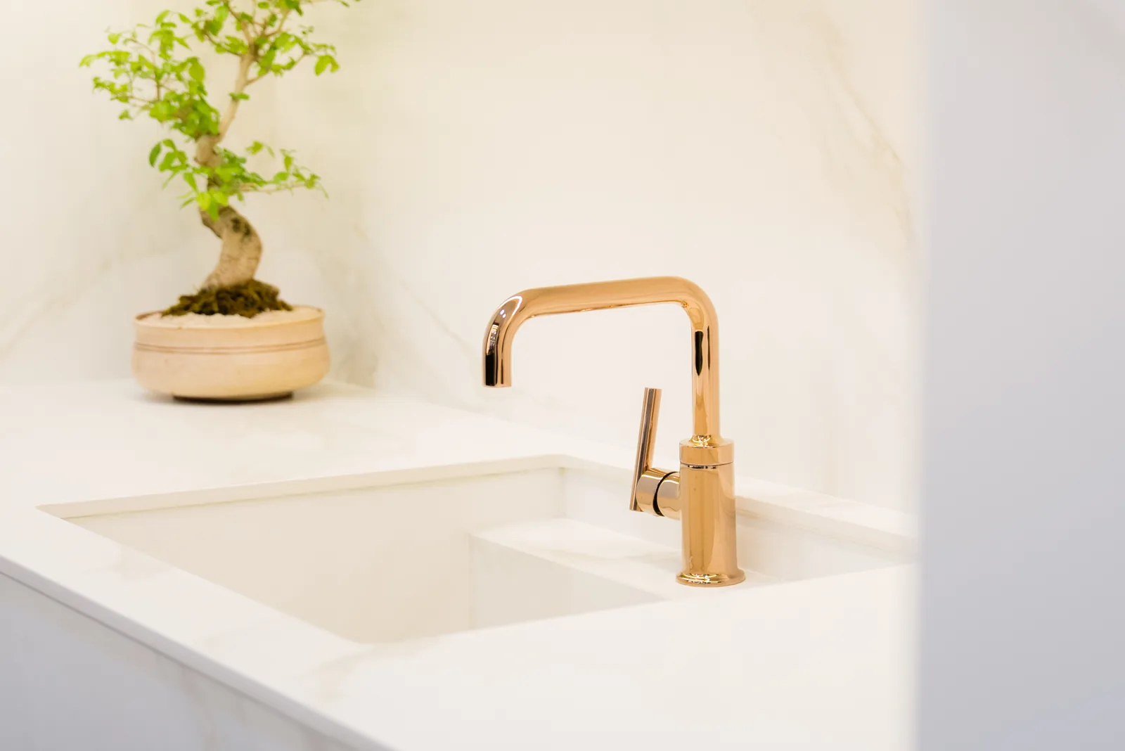 Fabricated pale stone basin with a rectangular bowl and gold tap.