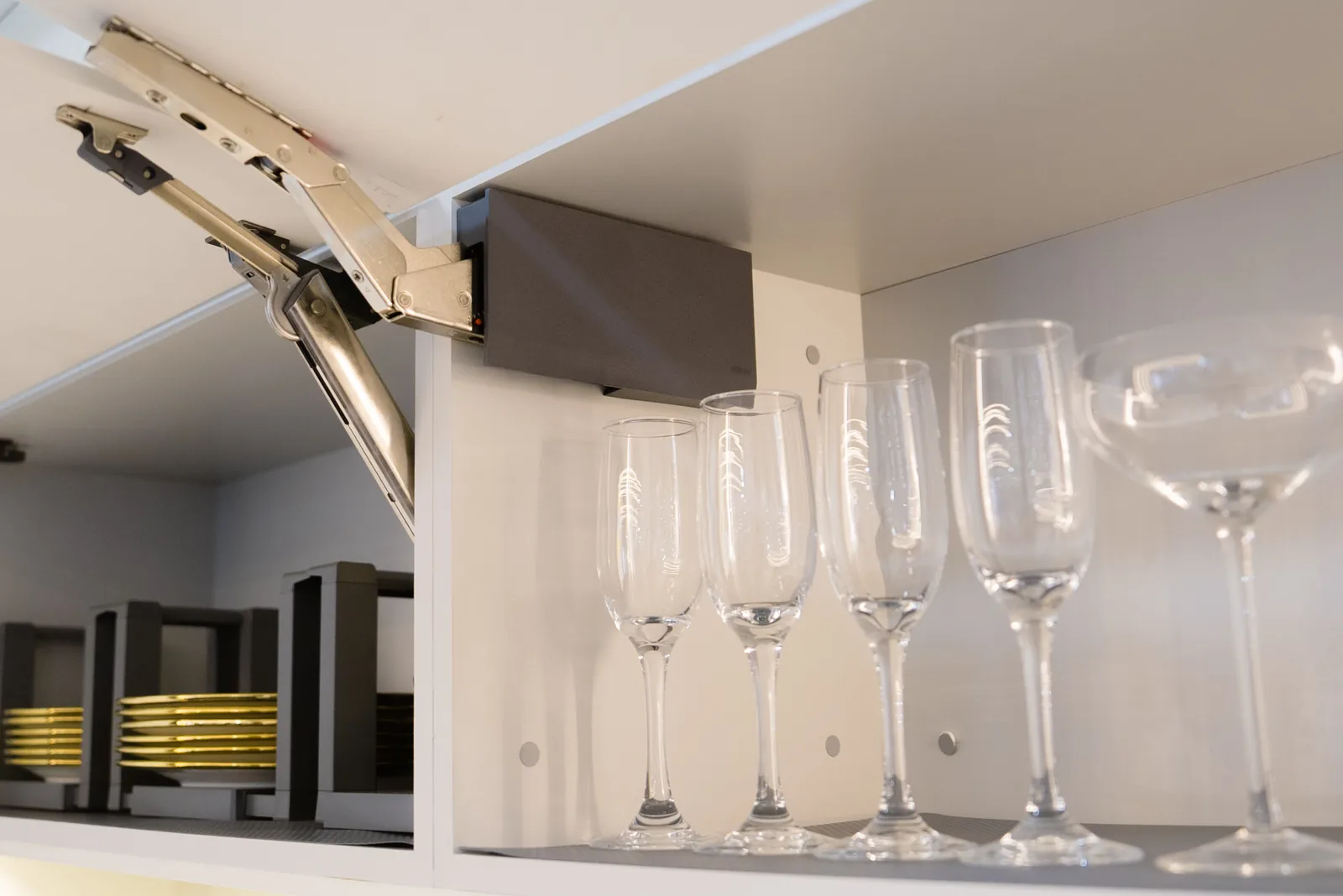 Raised cupboard front with its lift mechanism visible above glass storage.