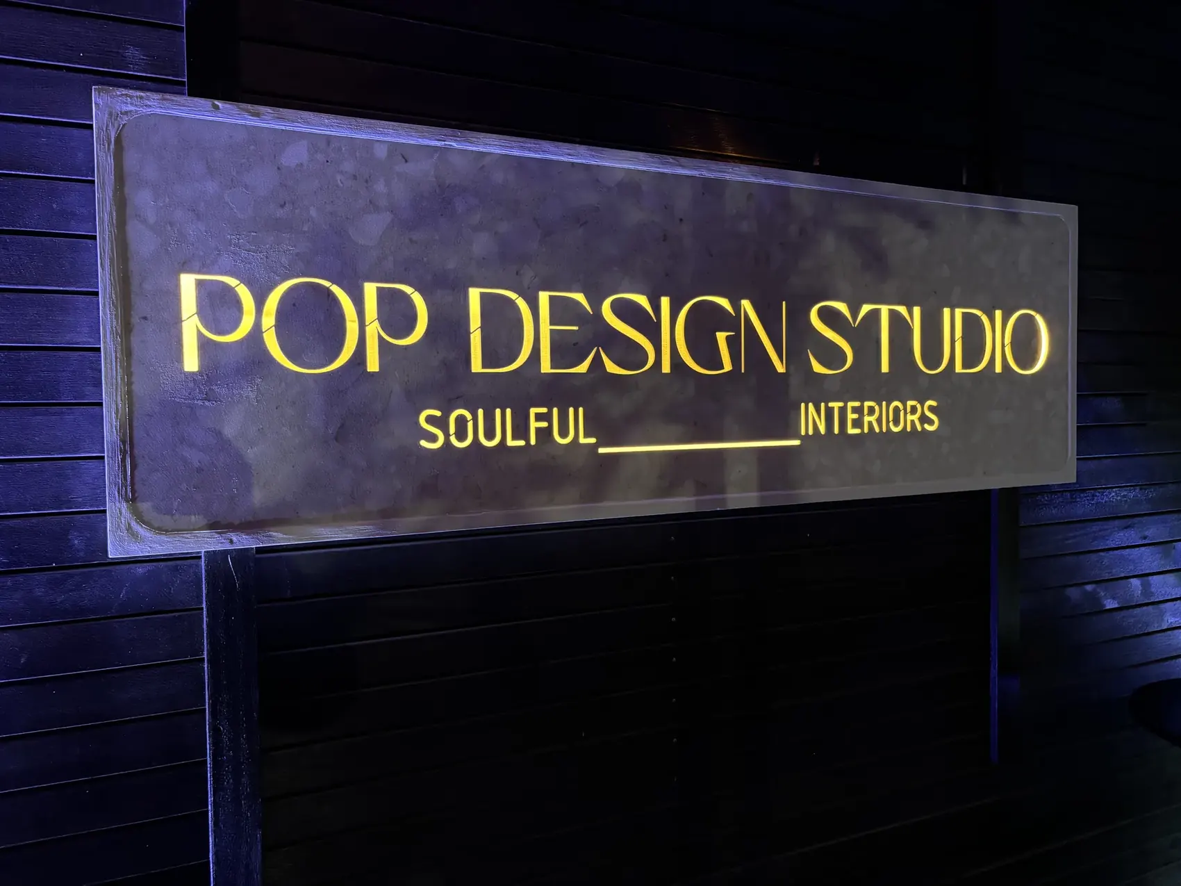 Illuminated lettering on a stone-faced sign.