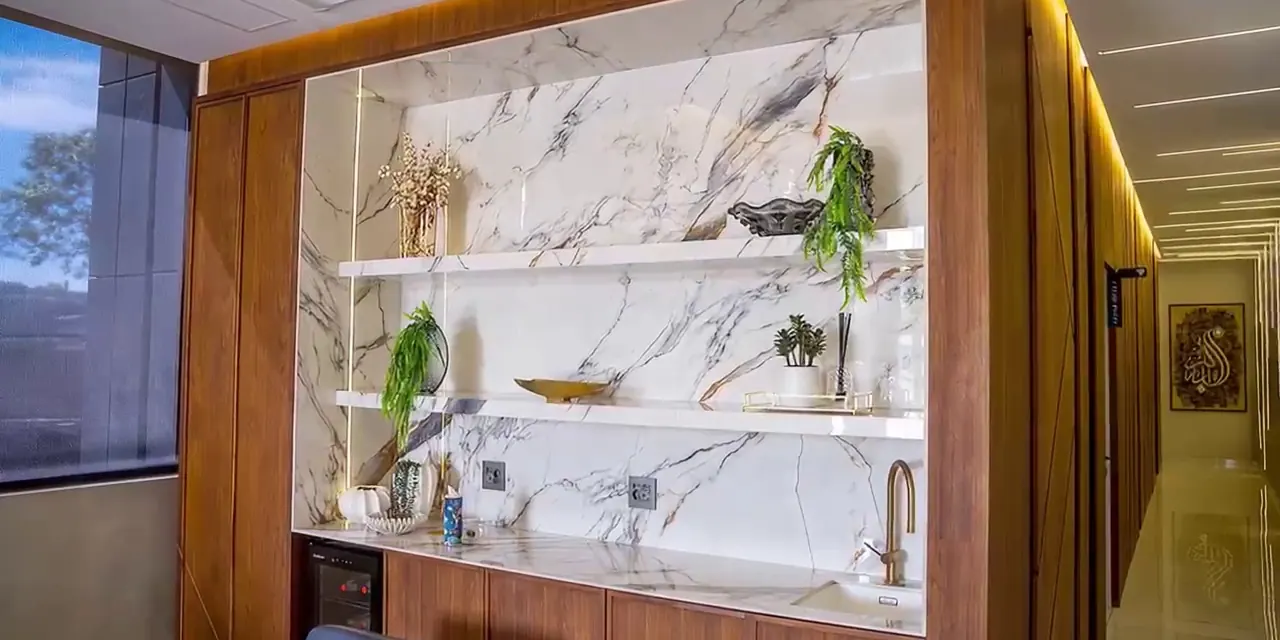 Office kitchenette with lit stone wall and counter.