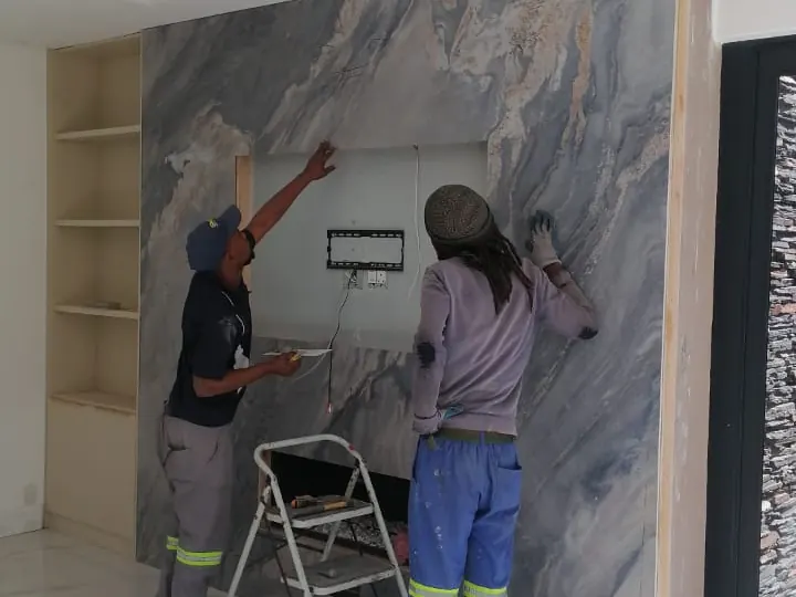 Installers working at stone fireplace wall.