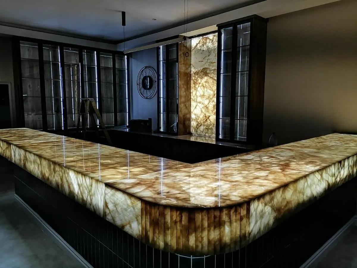 Illuminated stone bar and wall panel seen at an angle.