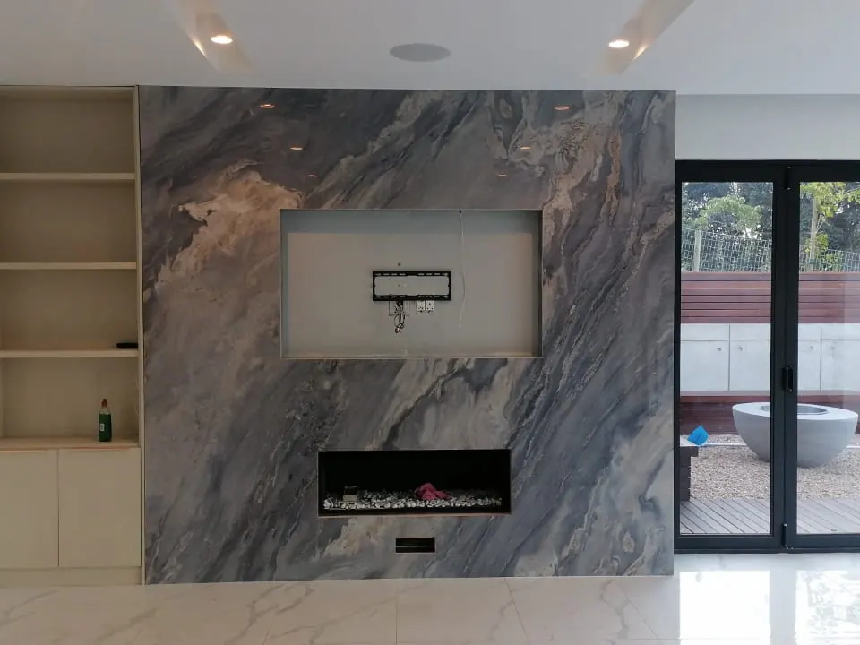 Veined stone fireplace wall with a recessed television mounting area.