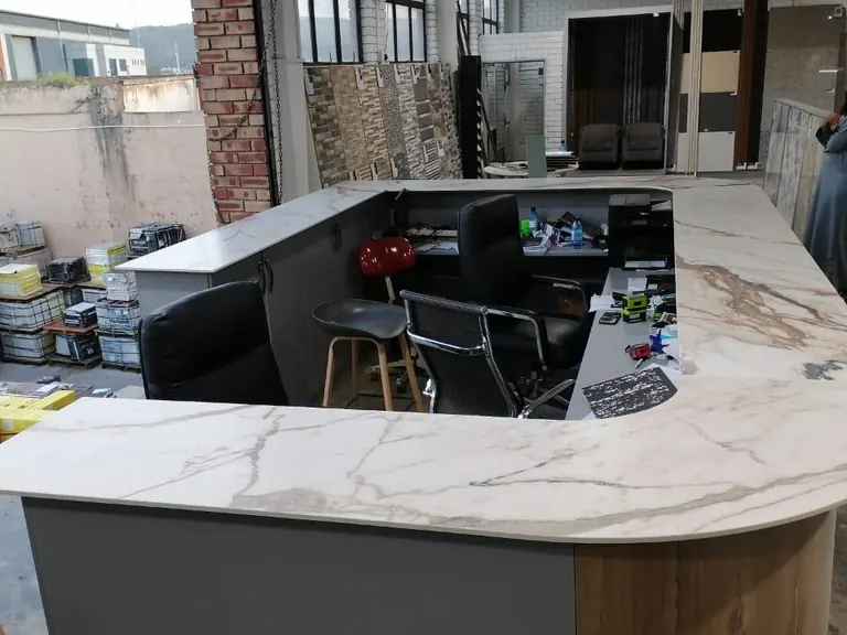 Curved stone-faced reception counter with seating behind it.