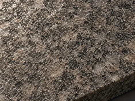 Leathered warm-grey granite face with shallow uneven mineral relief and small highlights in grazing light.