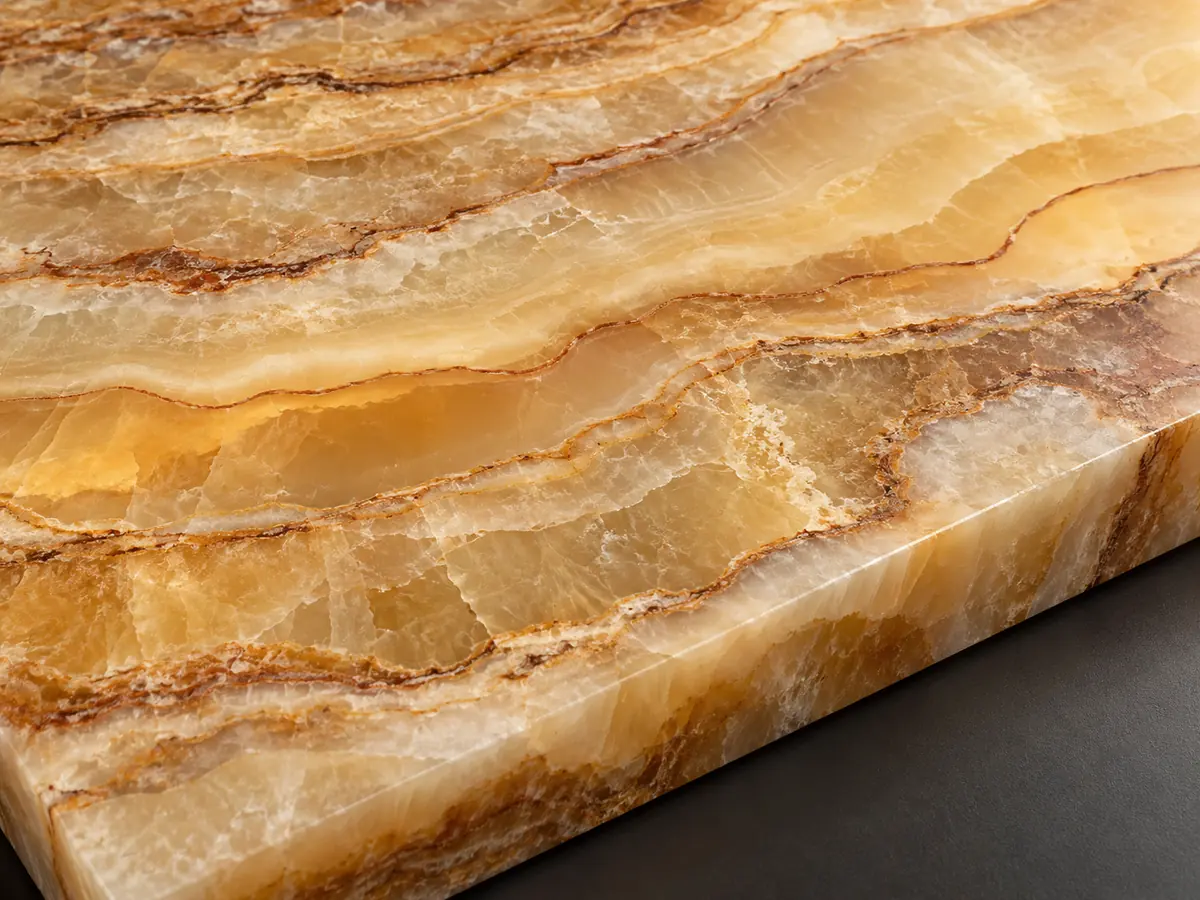 Honey-coloured onyx sample with irregular ivory bands, brown seams and softly lit translucent areas.