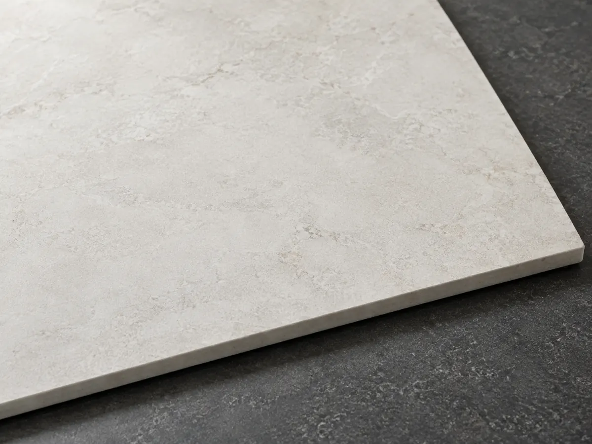 Pale sintered surface sample with subtle mineral clouding and a slim straight edge on a dark tabletop.