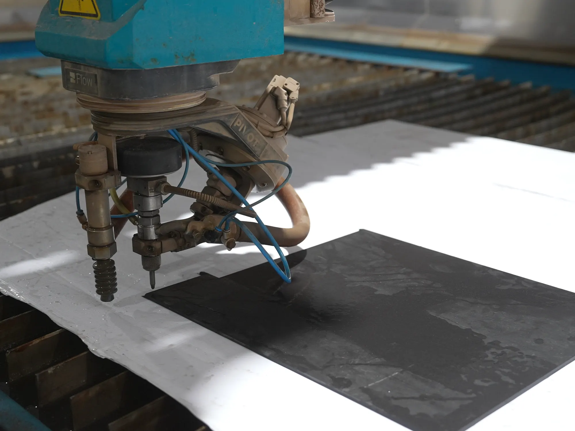 Waterjet head cutting a stone slab.