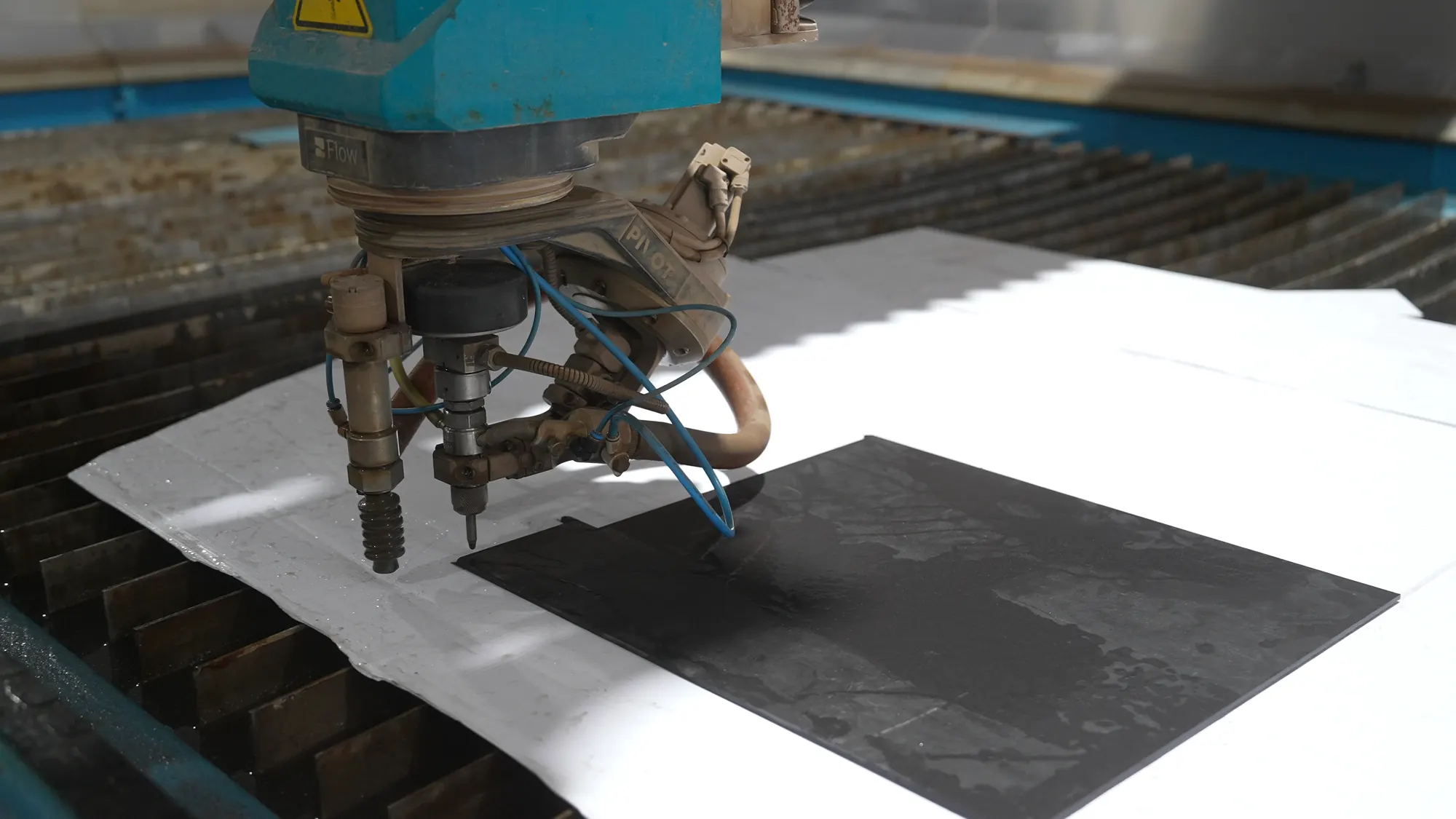 Waterjet head cutting a stone slab.